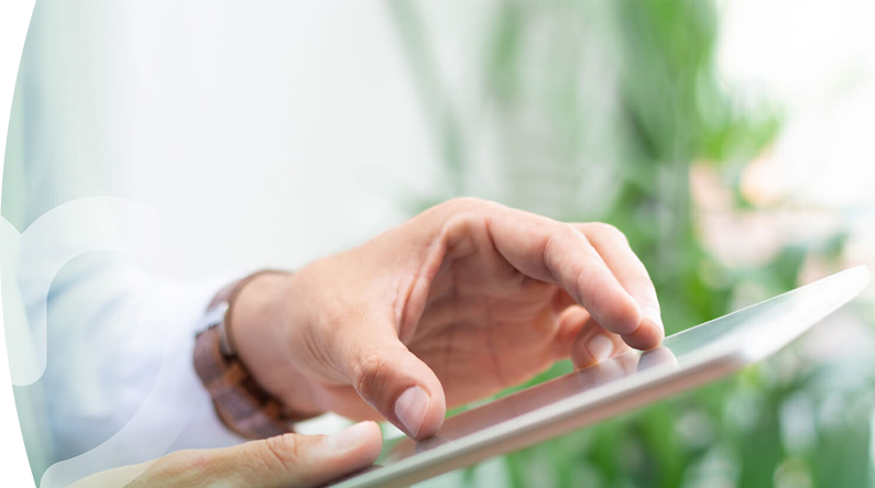 Mano de una persona usando una tablet con el dedo, en un entorno luminoso y natural