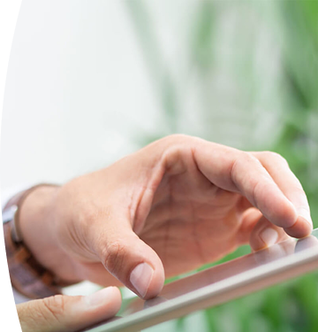 Mano de una persona usando una tablet con el dedo, en un entorno luminoso y natural