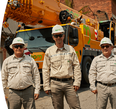 Fotografía de tres trabajadores de EPM con casco y uniforme posan frente a un camión grúa de mantenimiento