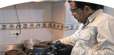 Técnico de EPM revisa un medidor de gas en una cocina mientras la estufa está encendida.