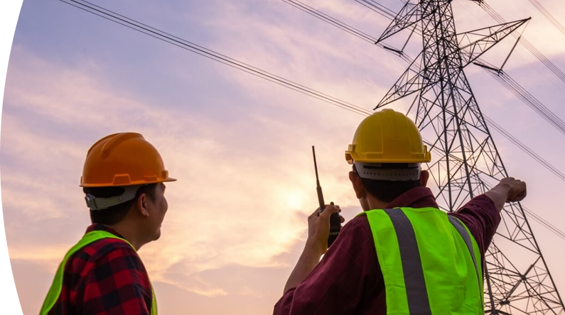 Banner "Energía constructor y urbanizador" con imagen de dos trabajadores con cascos y chalecos reflectantes observan y señalan una torre electrica al atardecer