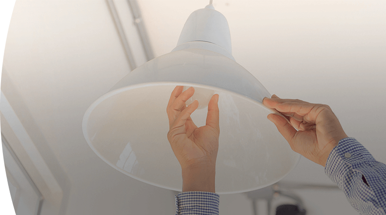 persona ajustando una lámpara de techo con ambas manos