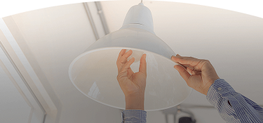 persona ajustando una lámpara de techo con ambas manos