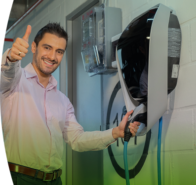 Hombre sonriente conectando su carro eléctrico en una estación de carga instalada en un parqueadero cubierto