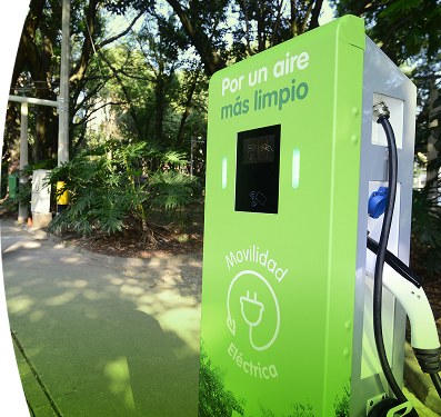 Banner ''Estaciones con modalidad de pago tarjeta'' carro eléctrico de EPM cargando en una estación pública rodeada de vegetación