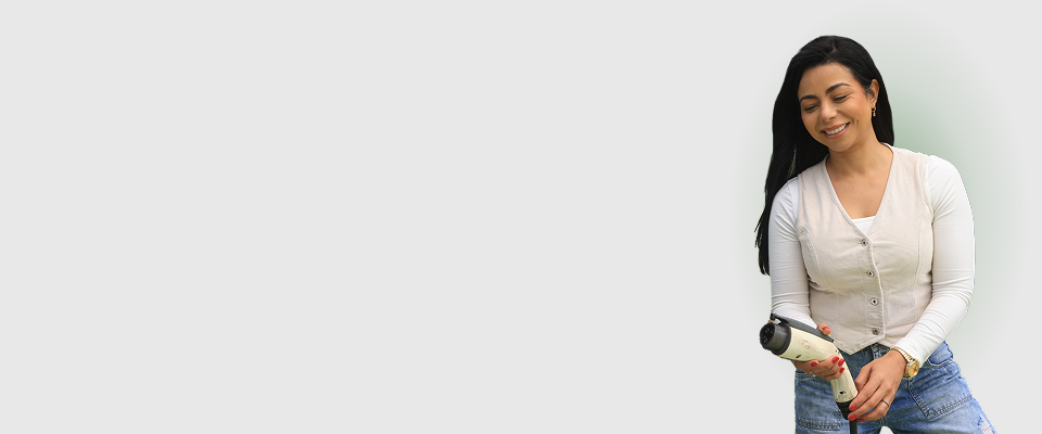 Mujer sonriente sostiene con sus manos un conector de carga