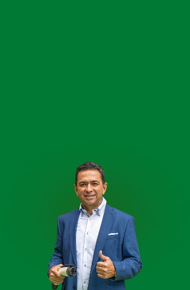 Hombre sonríe levantando el pulgar mientras con la otra mano sostiene el conector de carga