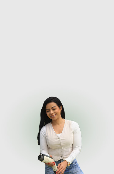 Mujer sonriente sostiene con sus manos un conector de carga