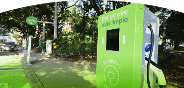 Banner ''Estaciones con modalidad de pago tarjeta'' carro eléctrico de EPM cargando en una estación pública rodeada de vegetación
