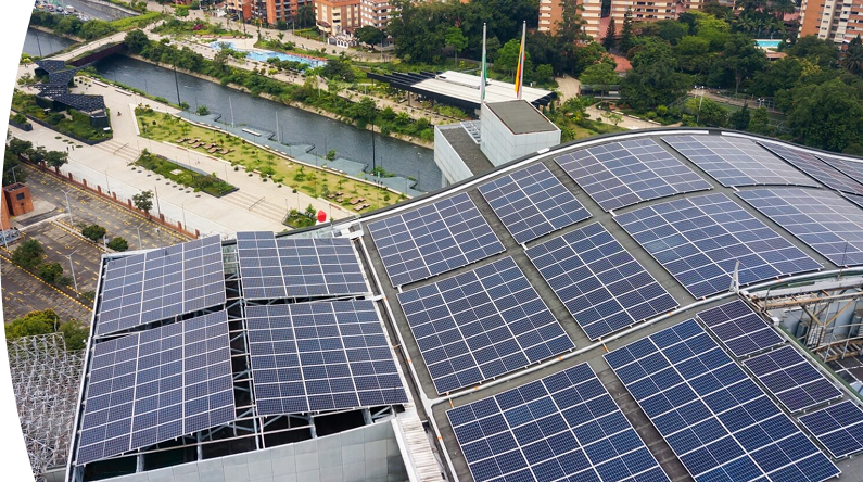 Banner ''Preguntas frecuentes'' paneles solares instalados en el techo de un edificio urbano junto a un río y zonas verdes, generando energía solar renovable