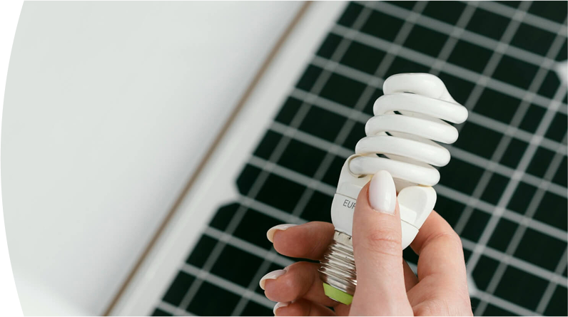 Banner ''Tipos de energía'' mano sosteniendo un bombillo ahorrador frente a un panel solar como símbolo de energía renovable y eficiencia energética