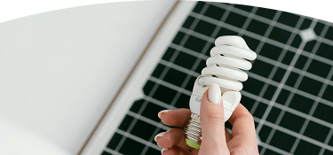 Banner ''Tipos de energía'' mano sosteniendo un bombillo ahorrador frente a un panel solar como símbolo de energía renovable y eficiencia energética