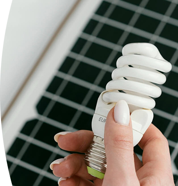 Banner ''Tipos de energía'' mano sosteniendo un bombillo ahorrador frente a un panel solar como símbolo de energía renovable y eficiencia energética