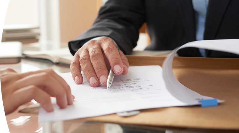 Mano de una persona señalando y revisando un documento durante un proceso de firma o validación