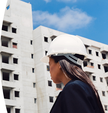 Mujer con un casco blanco viendo un edificio en construcción