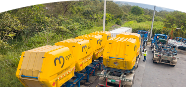 Tractocamiones con grandes contenedores amarillos marcados con el logo de EPM, alineados en una estación de carga