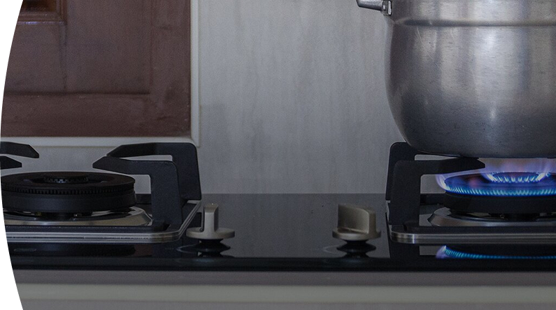 Estufa de gas encendida con llamas azules con una olla sobre uno de las bocas