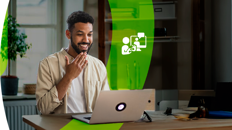 Hombre frente a un computador realiza gestos de lenguaje de señas durante una videollamada.