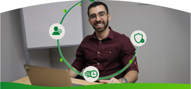 Hombre sonriente trabaja en un computador portátil mientras alrededor aparecen íconos relacionados con actualización de datos, seguridad y gestión digital.