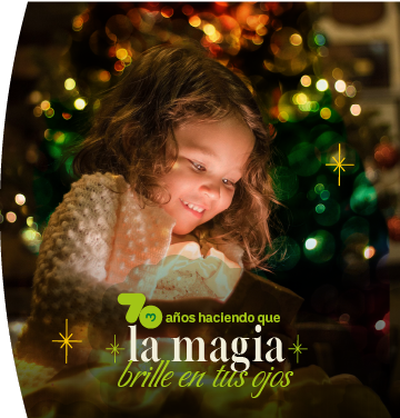Niña sonriente abre un regalo mágico bajo las luces de un árbol de Navidad, con un diseño gráfico a la izquierda que celebra "70 años haciendo que la magia brille en tus ojos".