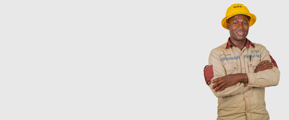 Trabajador de EPM con uniforme beige y casco amarillo de gas, cruzando los brazos y sonriendo sobre fondo gris