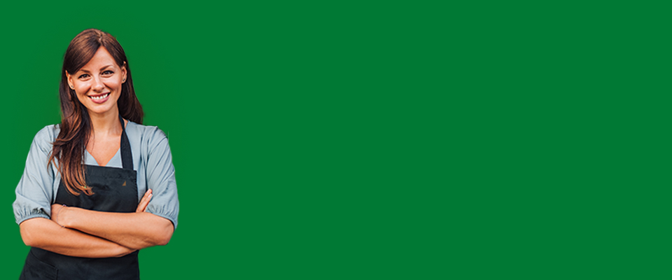 Trabajador de EPM con uniforme beige y casco amarillo de gas, cruzando los brazos y sonriendo sobre fondo gris