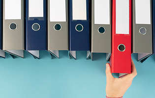 Mano toma una carpeta roja entre archivadores de colores sobre fondo azul