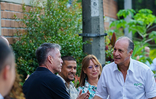 Representante de EPM saluda a miembros de la comunidad durante un encuentro en un entorno urbano verde