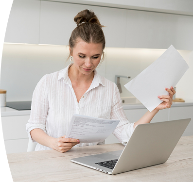 Mujer en la cocina revisa documentos en una laptop