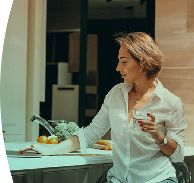 mujer en la cocina de su casa, tiene un vaso de agua en la mano 