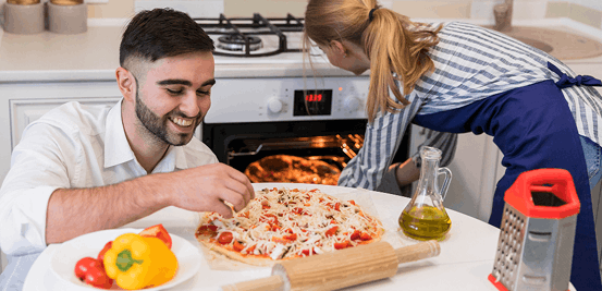 Fotografía de hombre y mujer cocinando una pizza en una cocina