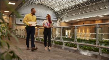 Conoce a "EPM Contigo". El acceso a esta información tiene una imagen de dos personas caminando en un pasillo moderno con plantas y luz natural.