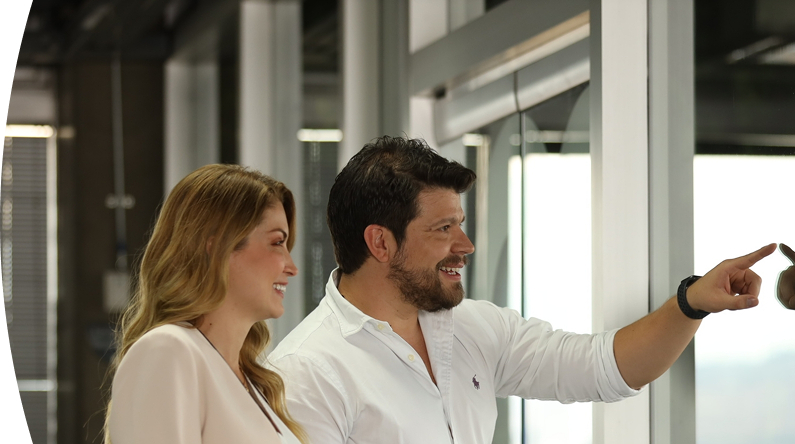 Dos personas sonríen mientras observan y señalan una pantalla en una oficina moderna