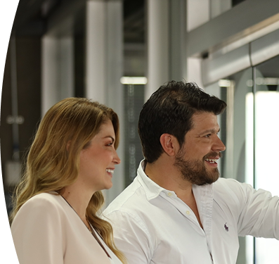 Dos personas sonríen mientras observan y señalan una pantalla en una oficina moderna