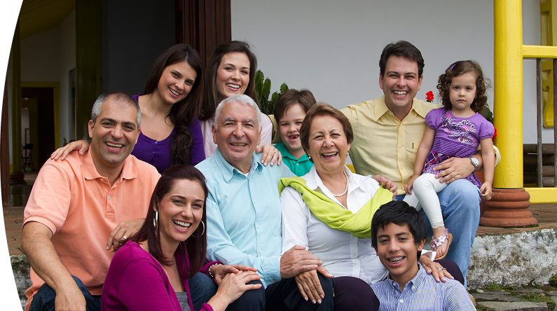Familia multigeneracional reunida en la entrada de una casa, sonriendo y compartiendo un momento feliz