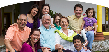 Familia multigeneracional reunida en la entrada de una casa, sonriendo y compartiendo un momento feliz