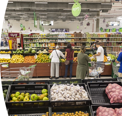 Personas comprando frutas y verduras en supermercado con señalética de EPM
