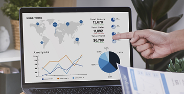Mano señalando una pantalla con gráficos financieros y datos de desempeño