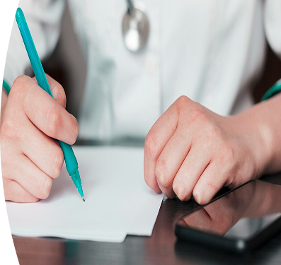 Persona escribiendo con un bolígrafo sobre una hoja de papel, con un teléfono móvil negro sobre la mesa.