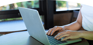 Persona escribiendo en el teclado de una computadora portátil sobre una mesa de madera