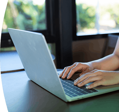Persona escribiendo en el teclado de una computadora portátil sobre una mesa de madera