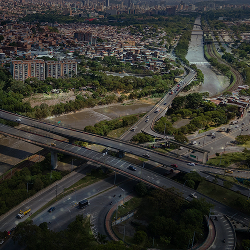 Vista aérea de una ciudad con múltiples avenidas, puentes y un río atravesando la zona, que refleja infraestructura urbana y movilidad.