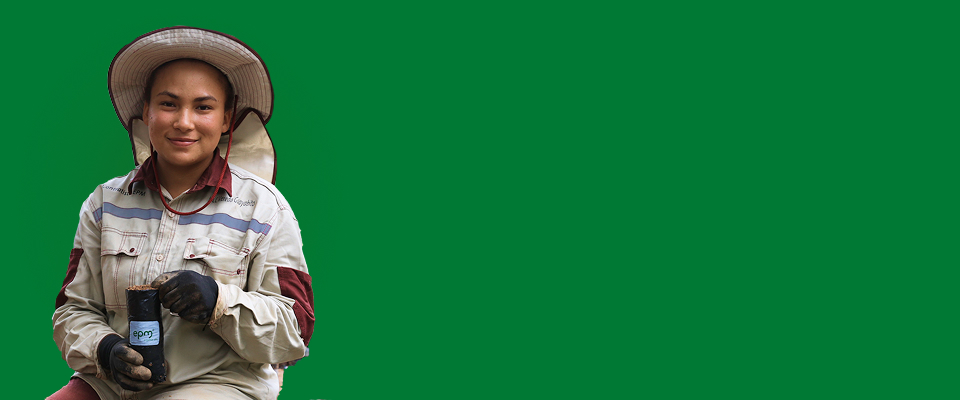 Hombre mayor sonriente con brazos cruzados, vestido con camiseta blanca, posando sobre fondo gris claro