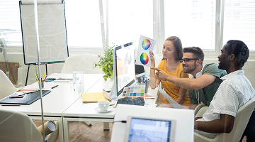  Equipo de trabajo analizando paletas de color frente a un computador en oficina iluminada