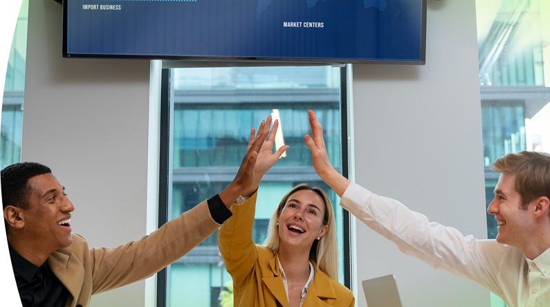 Tres personas en una sala de reuniones celebran un logro con un gesto de felicitación