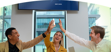 Tres personas en una sala de reuniones celebran un logro con un gesto de felicitación