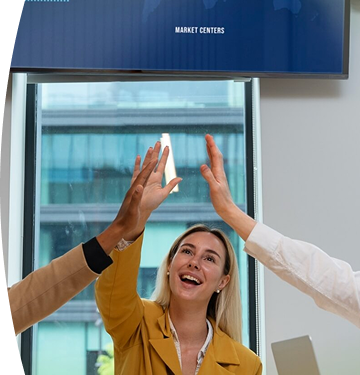 Tres personas en una sala de reuniones celebran un logro con un gesto de felicitación