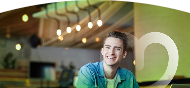 Joven sonriente con camisa de mezclilla en oficina moderna iluminada