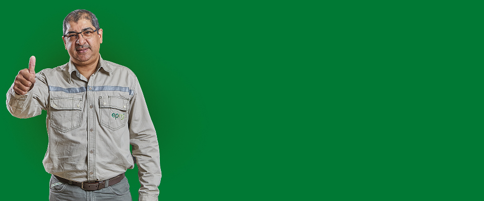 Colaborador de EPM con uniforme beige realiza gesto de aprobación con el pulgar arriba sobre fondo verde.
