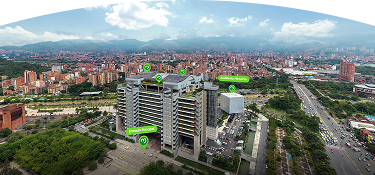 Vista aérea de la sede principal de EPM en Medellín, con señalización de la entrada principal y el Auditorio Himerio Pérez, rodeada de edificios, avenidas y montañas al fondo